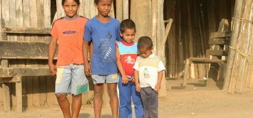 Vier Kinder vor einer Hütte in Südamerika