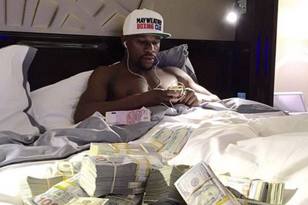 Floyd Mayweather in bed surrounded by piles of cash