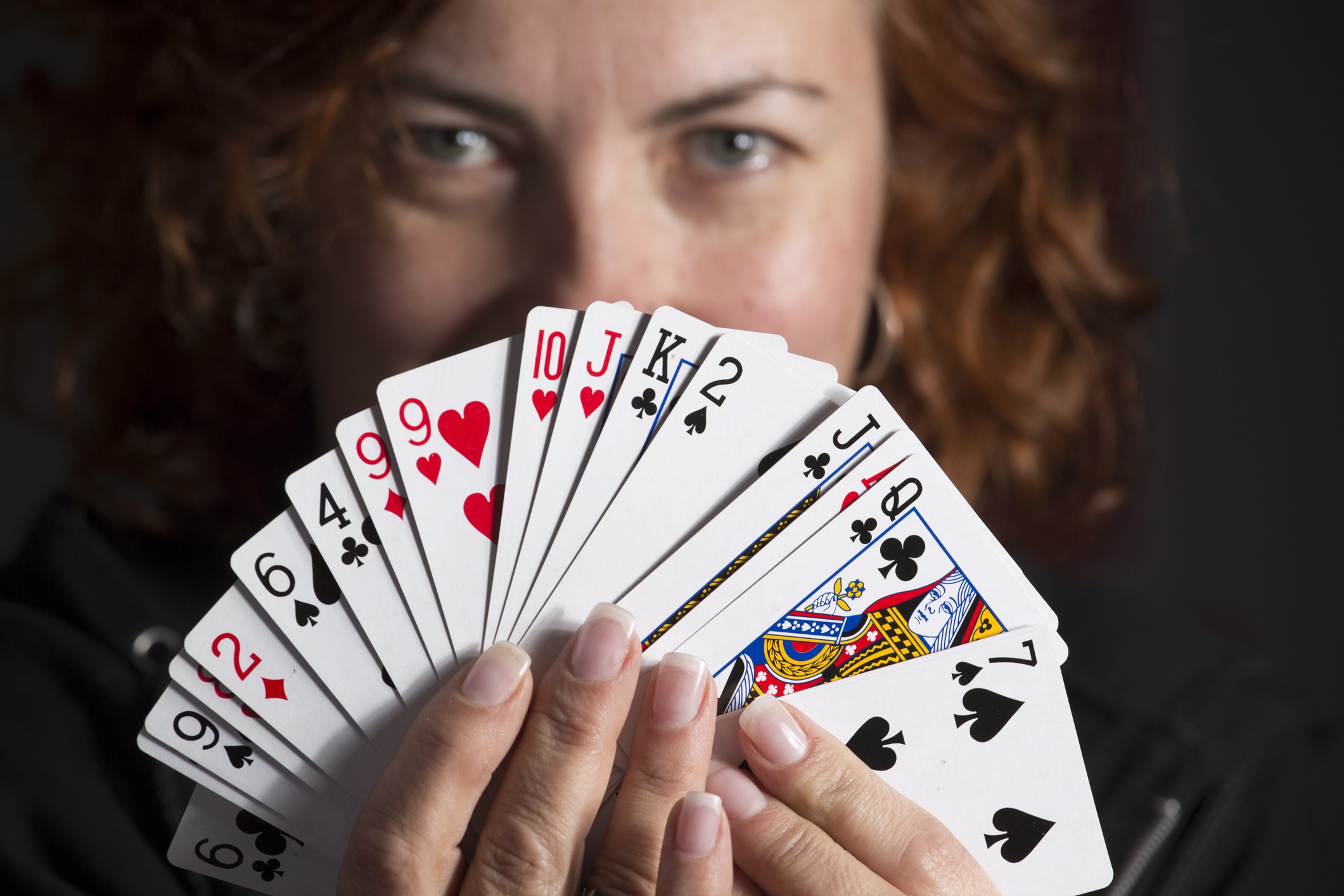 woman holding playing cards in front of her face