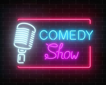 Neon comedy show sign with retro microphone on a brick wall background.