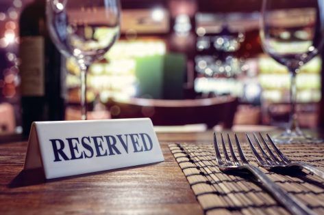 Restaurant reserved table sign with places setting and wine glasses ready for a party.