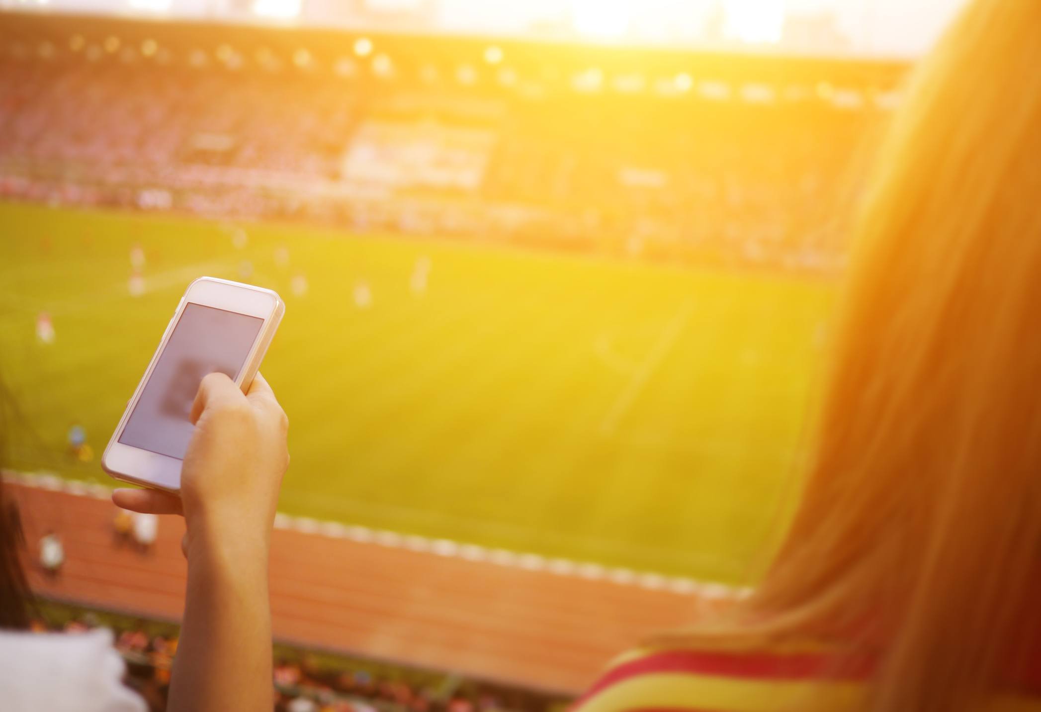 Women are using smart phone on the soccer stadium.