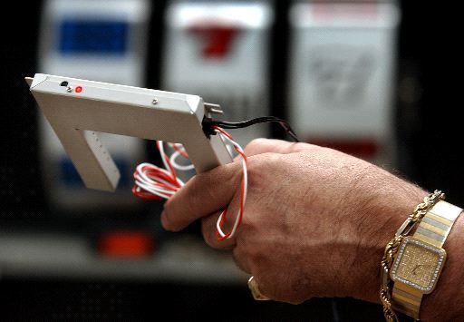 man's hand holding slot machine cheating device