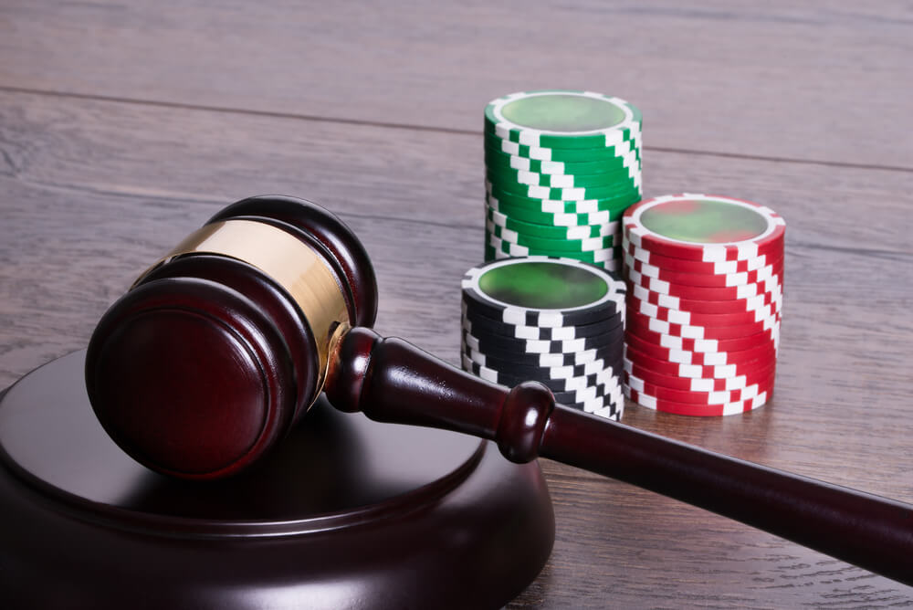 A gavel and casino betting chips on a brown wooded background