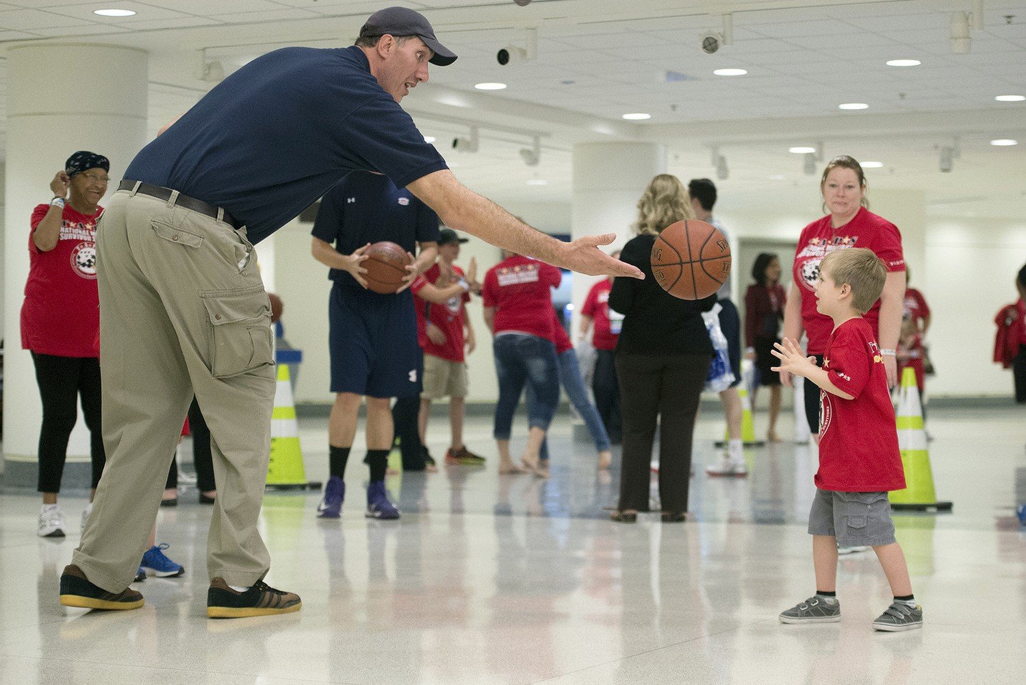 Former NBA player Gheorghe Mureșan tosses a basketball to a child 