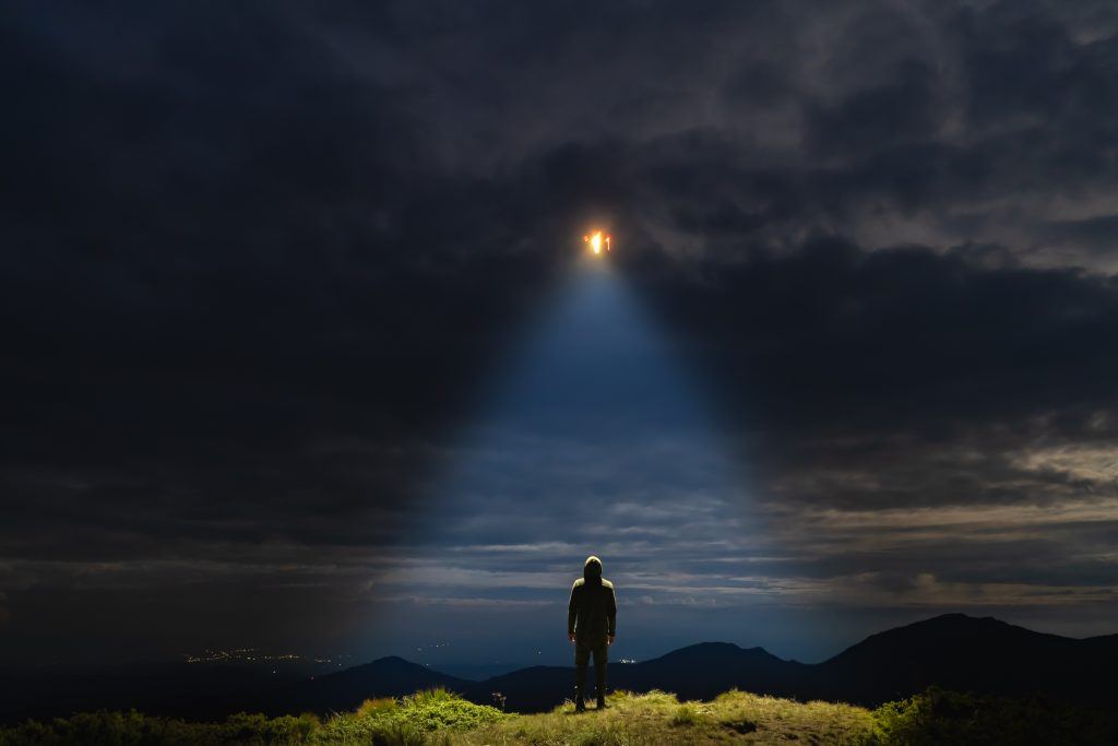 Person looking up at UFO at night
