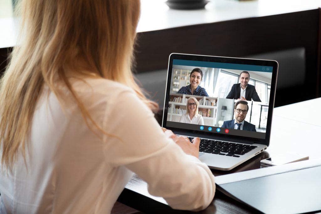 Woman using Webcam conference on laptop with four other people.