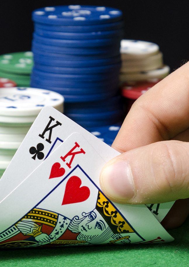 Hand in foreground holding pair of kings in poker
