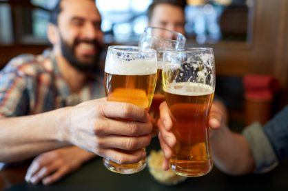 male friends drinking beer and clinking glasses at bar or pub