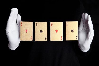 Playing cards trick with ace hands with gloves on black background