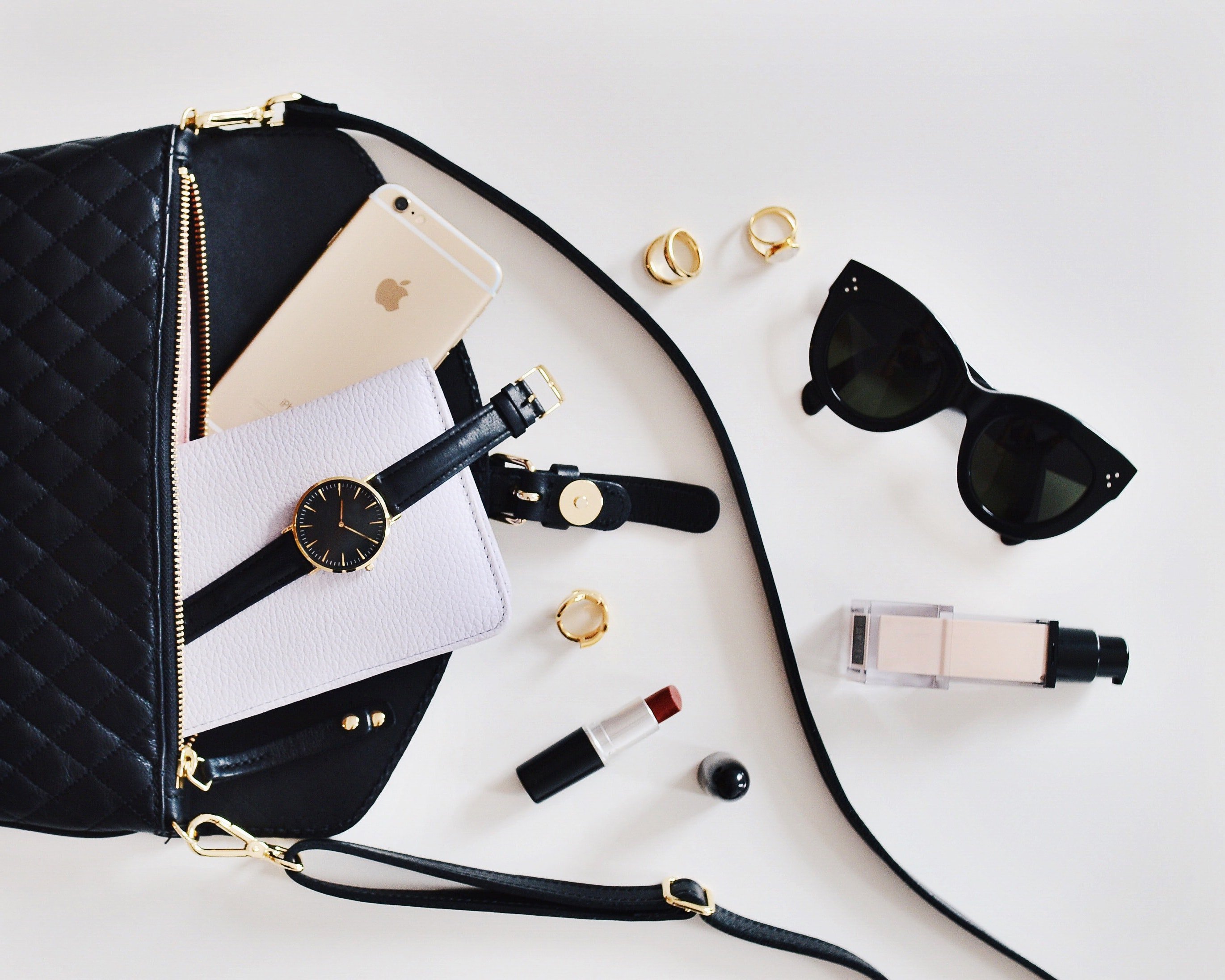 Women's sunglasses and black bag with watch and iPhone 6