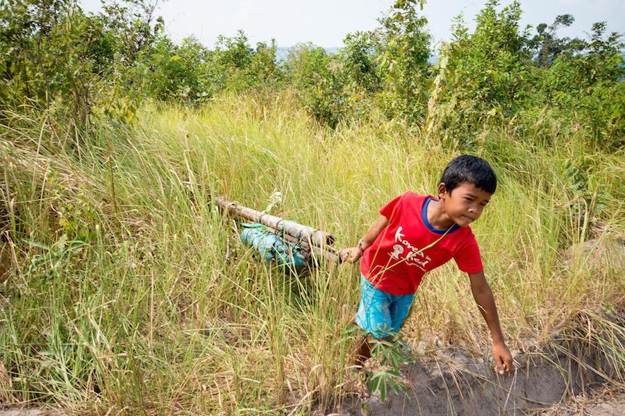 kid picking up rocket in field