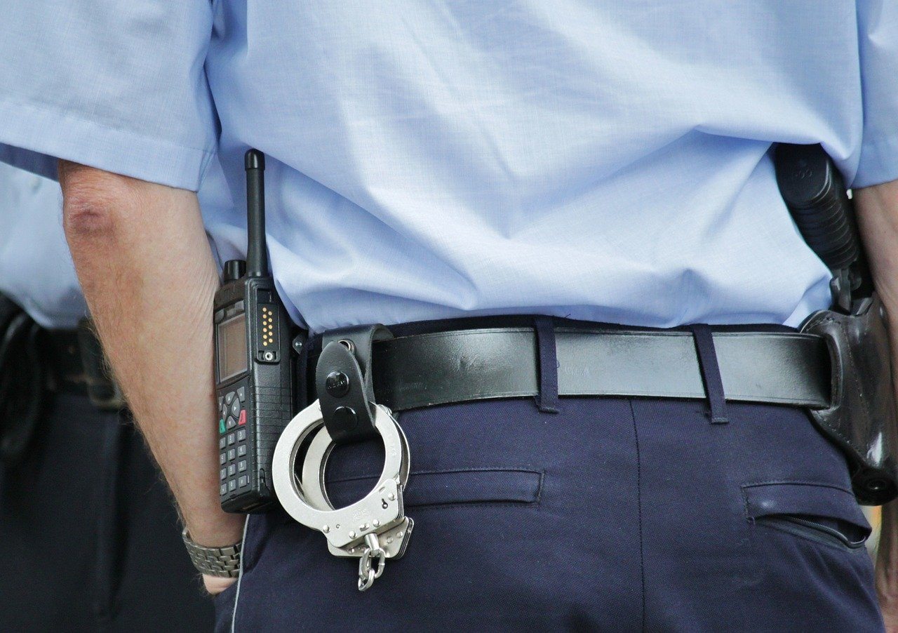 Polizist in Uniform mit Handschellen Funkgerät Pistole