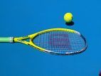 Tennisschlaeger und Ball auf blauem Platz