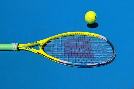 Tennisschlaeger und Ball auf blauem Platz