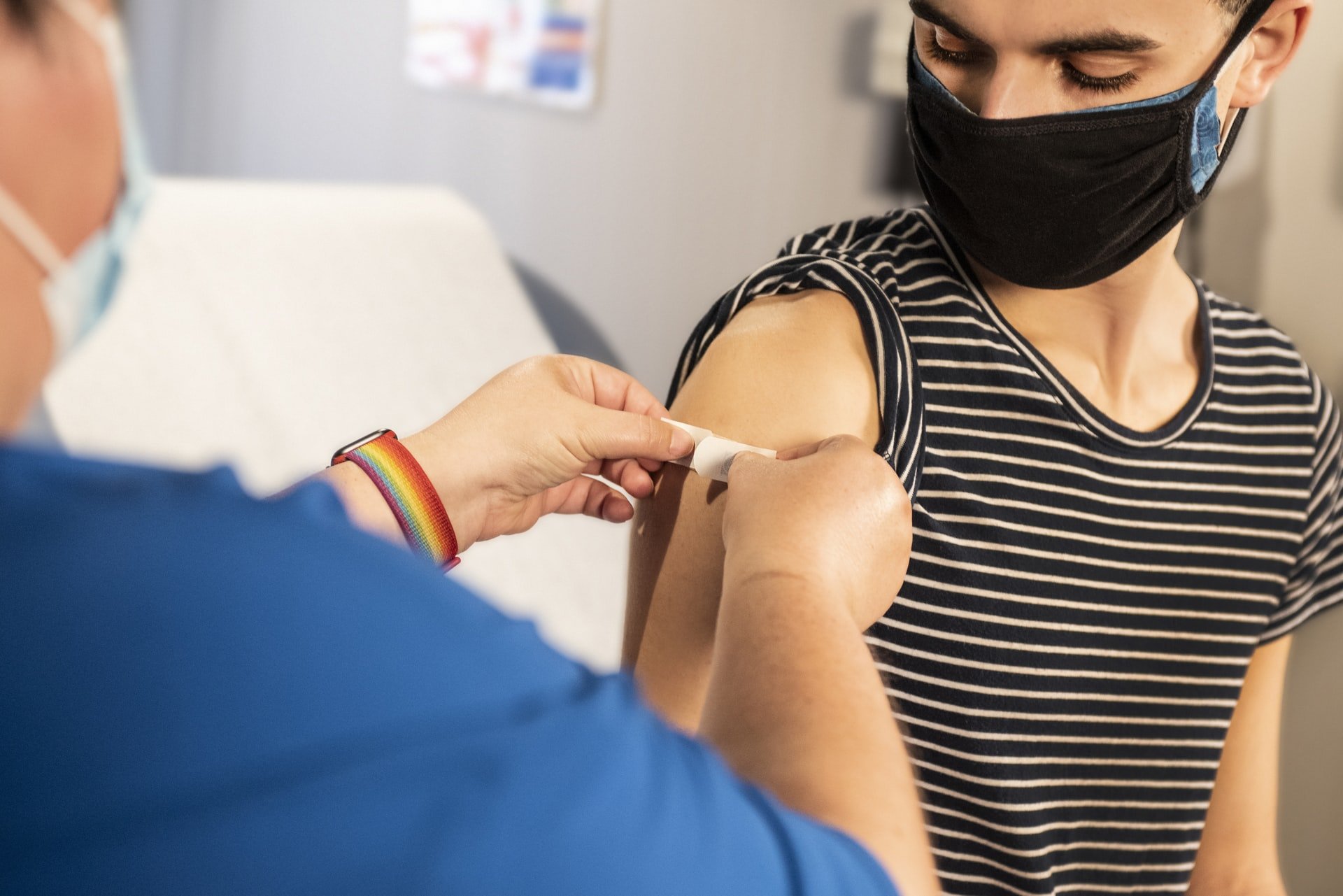 Mensch bekommt nach Impfung Pflaster auf Oberarm