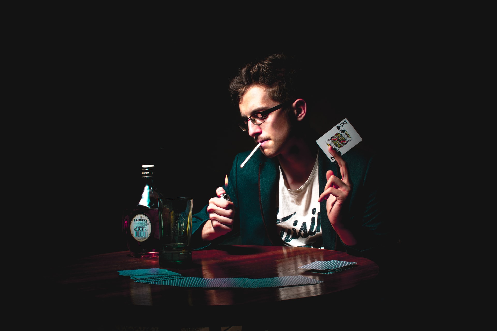 Mann mit Spielkarte und Zigarette, Flasche, Glas