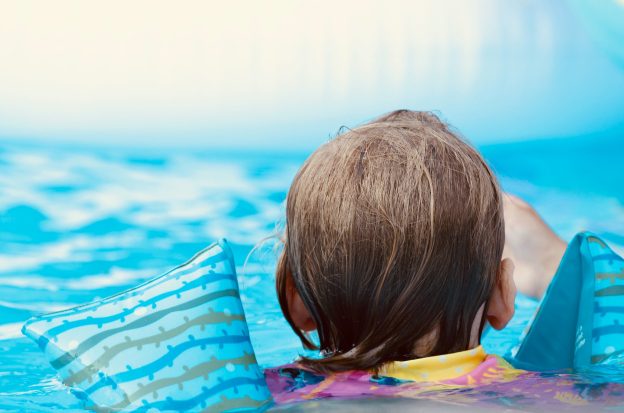 Kind mit Schwimmflügeln im Wasser