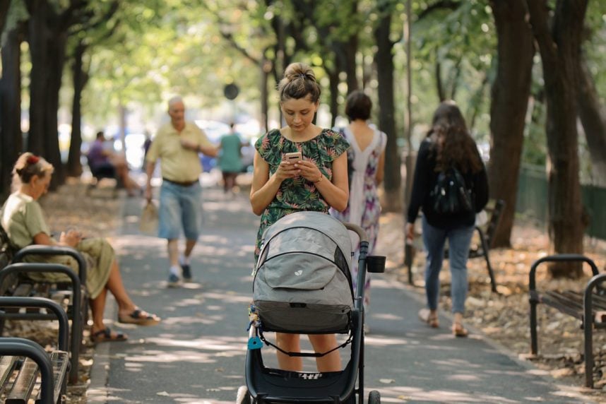 Frau mit Handy und Kinderwagen