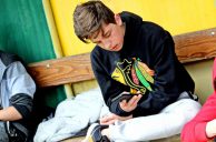 sitzender Jugendlicher mit Smartphone
