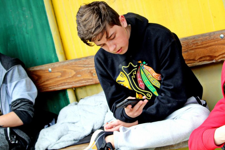 sitzender Jugendlicher mit Smartphone