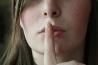 Frau legt Finger auf Lippen