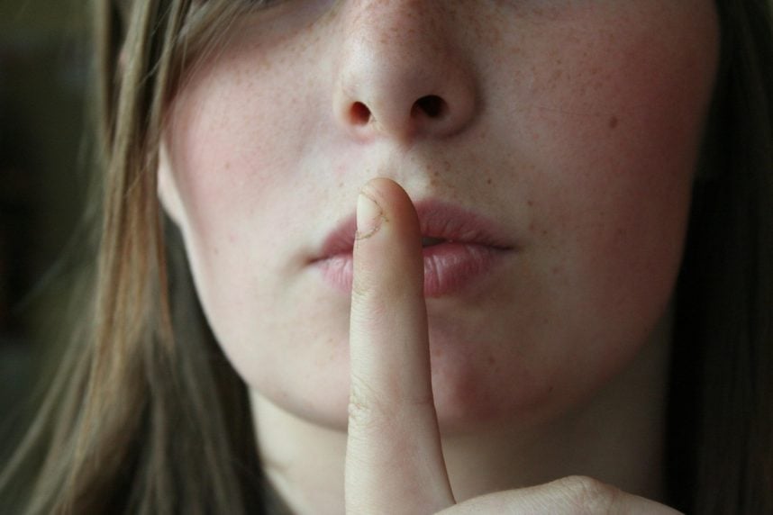Frau legt Finger auf Lippen