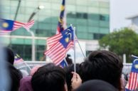 Menschen halten malaysische Flaggen