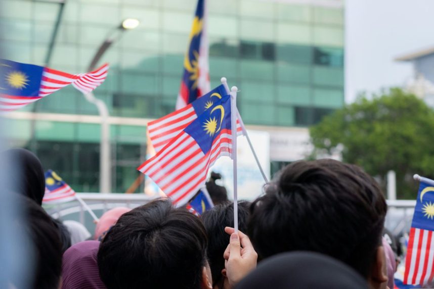 Menschen halten malaysische Flaggen