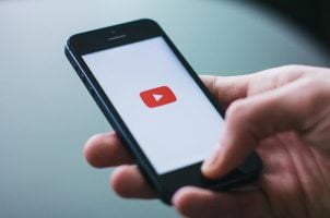 Hand hält Smartphone mit YouTube-App