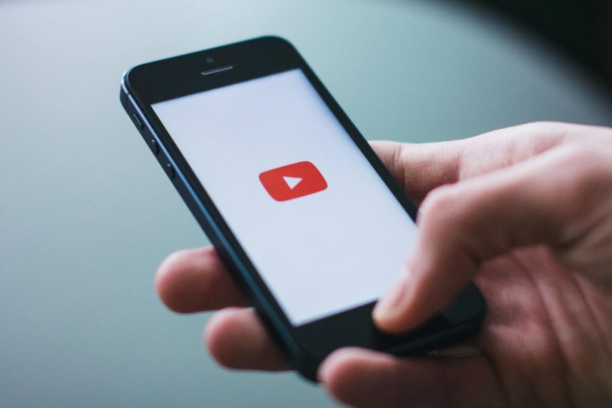 Hand hält Smartphone mit YouTube-App