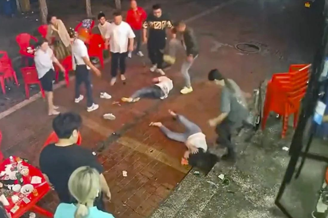 Two women lie on the ground after a group of men beat them up