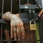 A prisoner leans on the bars of a Colombian jail cell