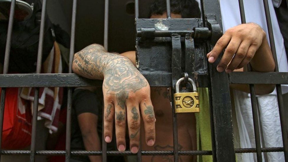 A prisoner leans on the bars of a Colombian jail cell