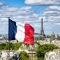 The French flag flies on a building with the Eiffel Tower in the background