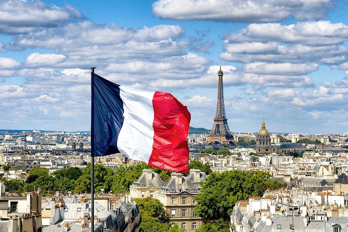 Bendera Prancis berkibar di gedung dengan Menara Eiffel di latar belakang
