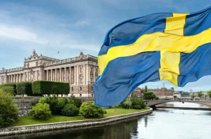 The Swedish flag with Stockholm Palace in the background
