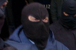 Hooded figures belonging to the 'Ndrangheta mafia are led away by Italian police