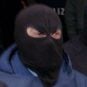 Hooded figures belonging to the 'Ndrangheta mafia are led away by Italian police