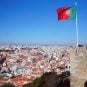 The Portuguese flag flies from a castle overlooking the city of Lisbon