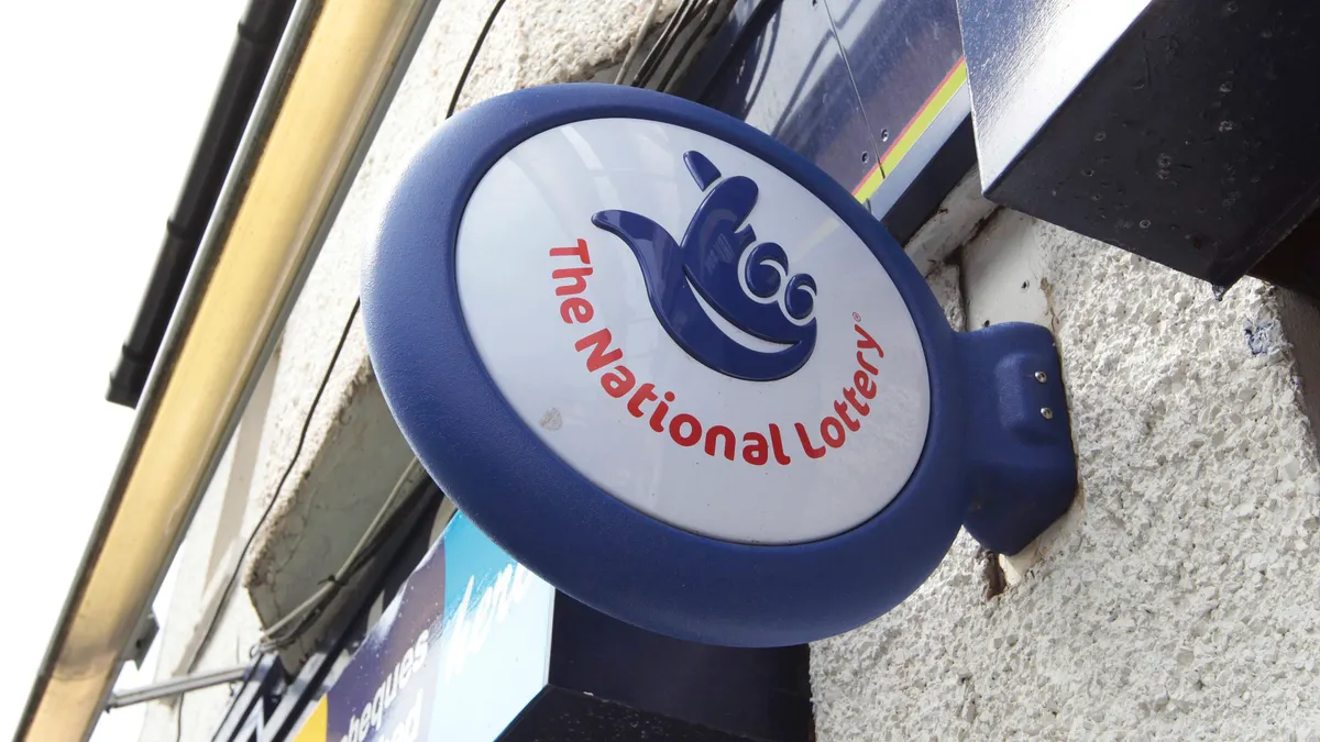 A UK National Lottery sign hangs over a vendor's store