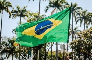 A man holds a tattered Brazilian flag