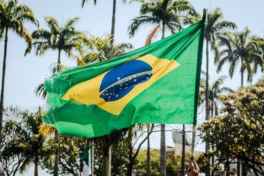 A man holds a tattered Brazilian flag