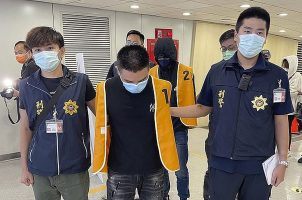 Police officers from the Taiwan Criminal Investigation Bureau escort two suspects who were deported from Bangkok and believed to be involved in scams