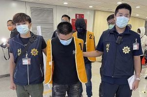 Police officers from the Taiwan Criminal Investigation Bureau escort two suspects who were deported from Bangkok and believed to be involved in scams