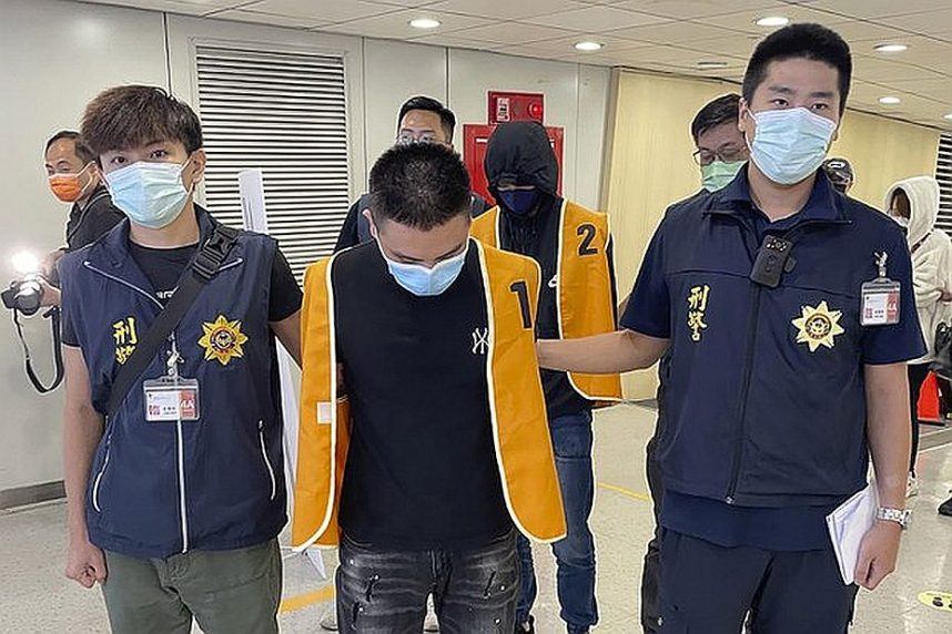 Police officers from the Taiwan Criminal Investigation Bureau escort two suspects who were deported from Bangkok and believed to be involved in scams
