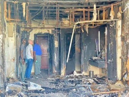 Investigators inspect a burnt-out hotel room at the Ramada Hotel and Casino in Guyana