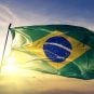 The sun shines behind the flag of Brazil