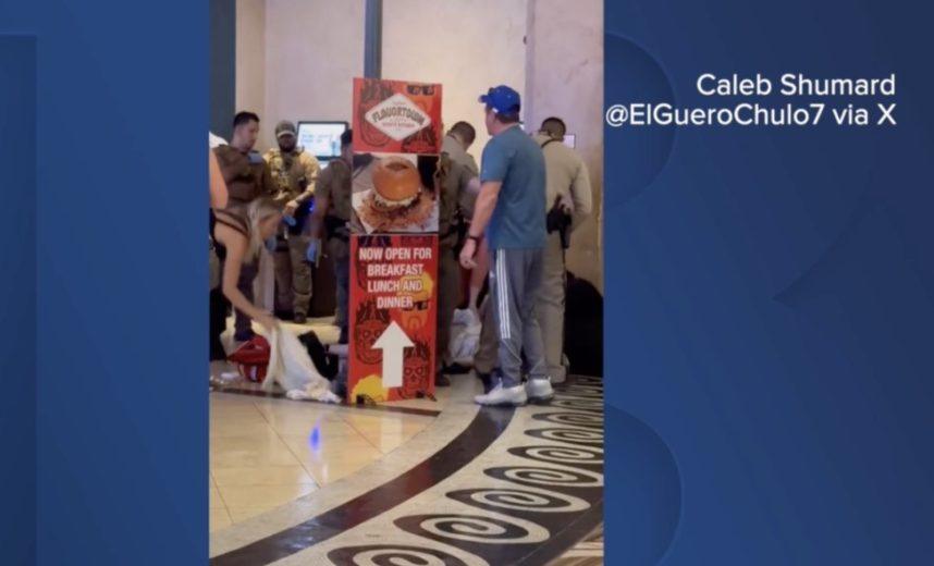 Security guards, police officers and passersby attend to a wounded man