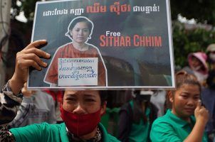 A NagaWorld worker holds a sign protesting the arrest of Chhim Sithar